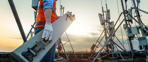 Technician installing signal equipment on a rooftop at sunset